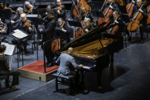Man playing piano, orchestra and conductor