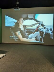 A video screen displaying a woman driving a car