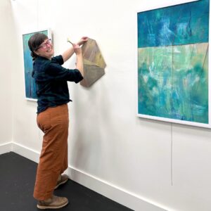 Woman nailing fabric to a gallery wall