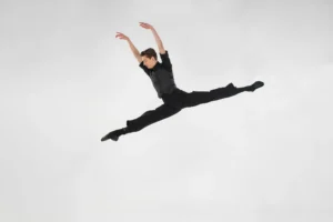 A male dancer in black mid-leap